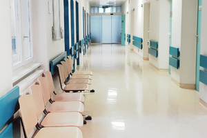 empty hospital hallway with a row of beige waiting room chairs. 
